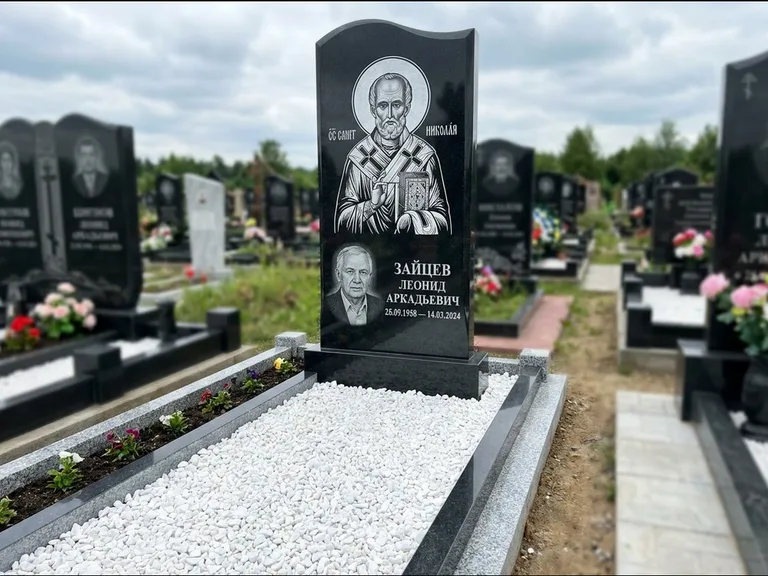 Памятник с гравировкой иконы: стела с крестообразным навершием — икона в резной рамке-киоте, газон без ограды, стриженая трава, работа «Раевская» в Якутске
