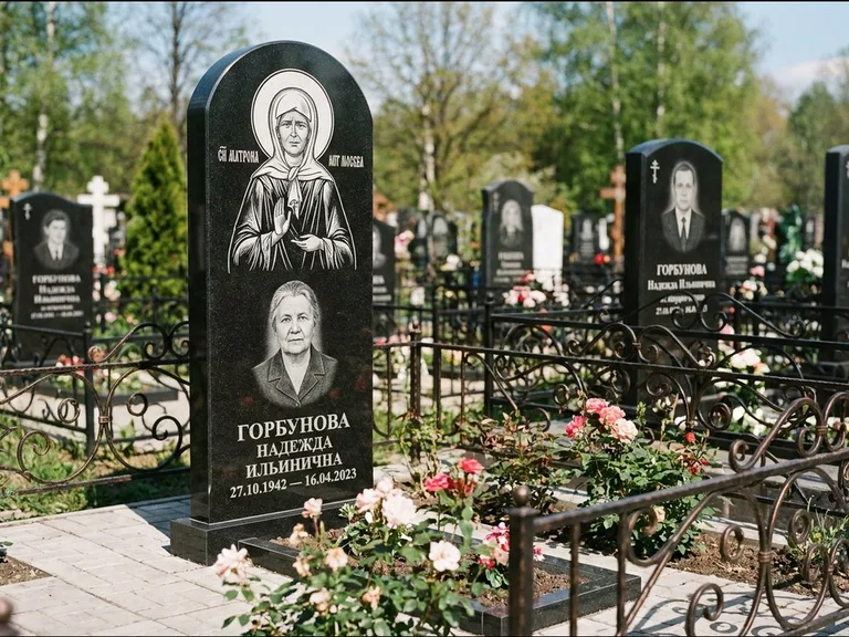 Памятник с гравировкой иконы: стела с арочным верхом и киотом под образ — гравировка образа Матроны Московской, гранитный цоколь с тёмной плиткой, работа «Ковалёв» в Якутске