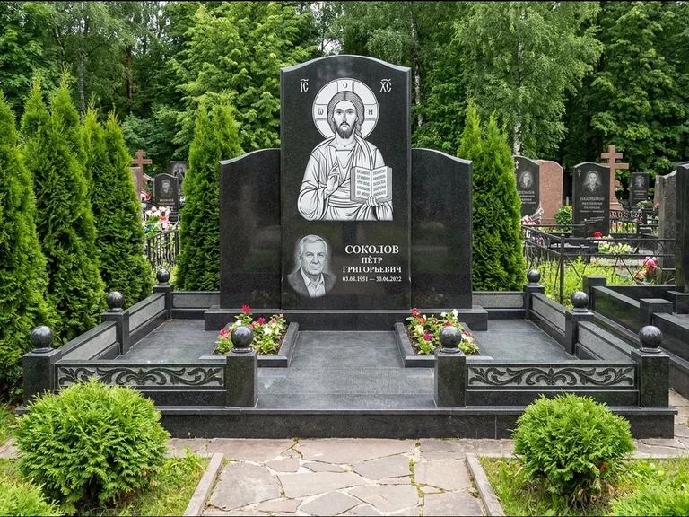 Памятник с гравировкой иконы: широкая горизонтальная лежачая плита-стела — икона в резной рамке-киоте, серая гравийная отсыпка с бордюром, работа «Богданова» в Якутске