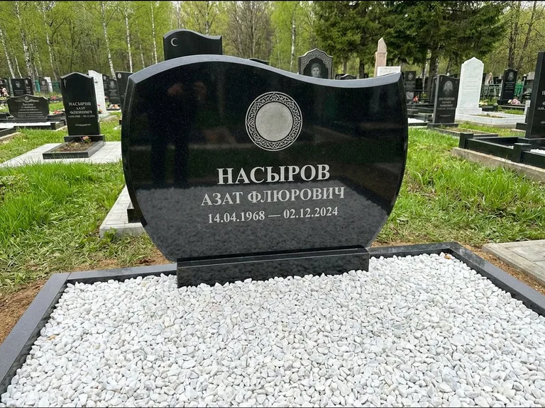 Мусульманский памятник: стела с волнообразным скошенным верхом — гравировка мечети под полумесяцем и звёздами, белая мраморная крошка с бордюром, работа «Насыров» в Якутске