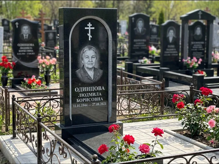 Памятник из чёрного гранита — скромная невысокая стела с крестом с терновым венцом, работа «Лаврентьева» в Якутске
