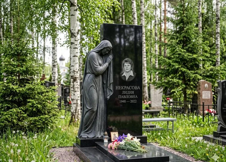Гранитная фигура скорбящего мужчины у чёрной стелы в Якутске